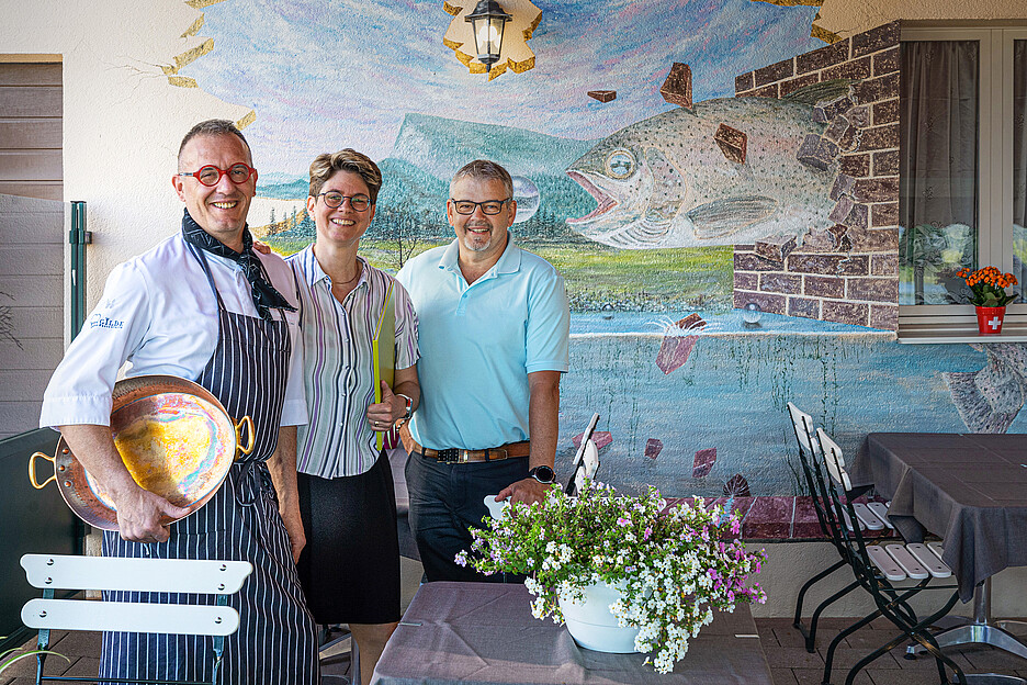 Erfolgreiche Lieferantenpartnerschaft: Das Gilde-Gastronomen-Paar Sylviane und Roberto Biaggi vom Restaurant du Lac in Le Pont am Lac de Joux zusammen mit Mario Grichting, Regionalverkaufsleiter für die Westschweiz und das Wallis der Lachsräucherei Dyhrberg AG (rechts im Bild).