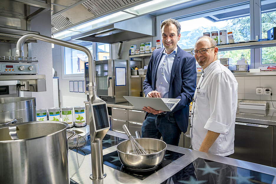 Gebietsverkaufsleiter Adrian Seeholzer von Menu System erklärt Küchenchef Patrick Weber, wie automatische Updates und Pfannenerkennung die Leistung des Herds stets auf dem neuesten Stand halten.