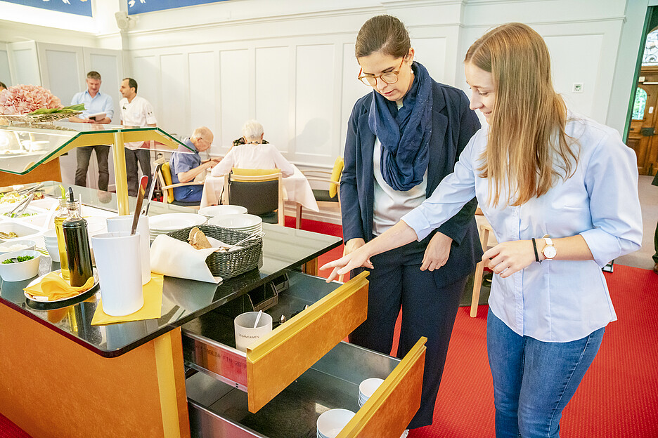Julia Menet von megaPlus erläutert die seitlichen Schubladen mit viel Stauraum, die Jil Rüesch (l.), Leitung Hauswirtschaft Haus Singenberg, besonders schätzt.