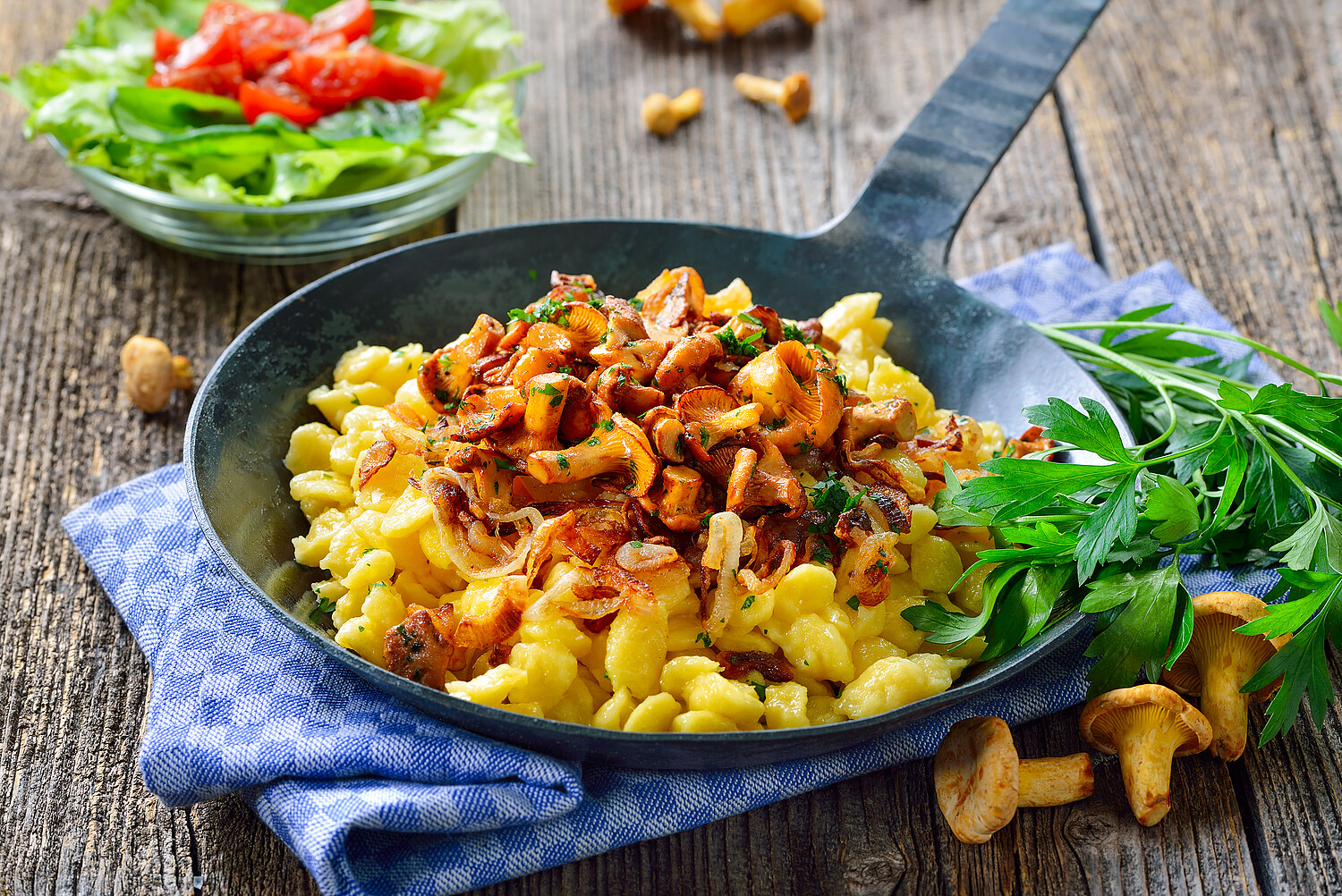 Schwäbische Spätzle mit frischen, gebratenen Pfifferlingen und Zwiebeln in der Pfanne rustikal serviert - Vegetarian Swabian spaetzle with fried chanterelles and onions served in a frying pan