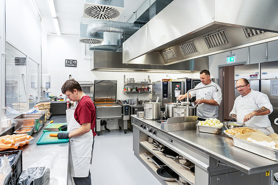 Die Küche wurde so geplant, dass Menschen mit Unterstützungsbedarf ausreichend Raum und Bewegungsfreiheit haben. Links: Martin Seiler beim Gemüse schneiden.